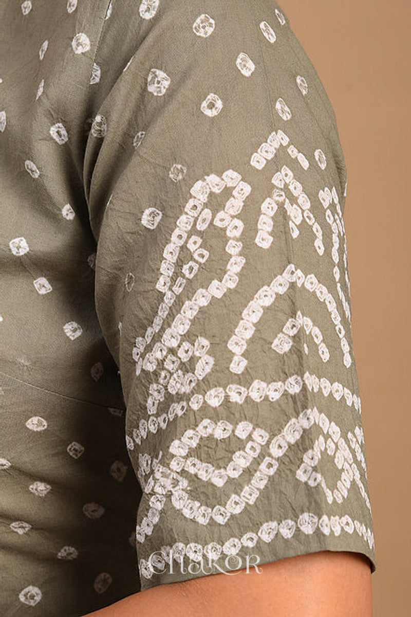 Woman wearing a handcrafted grey bandhani cotton blouse with intricate parrot motifs and boria buttons on front.