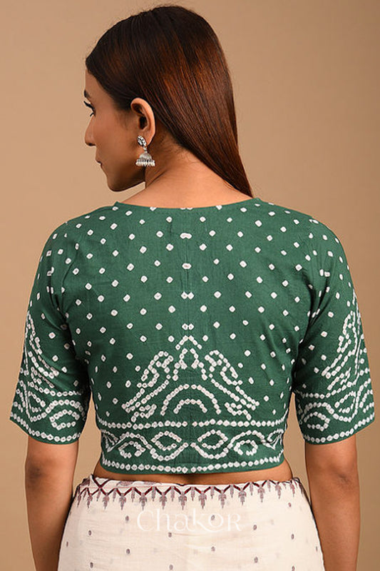 Woman wearing a handcrafted moss green bandhani cotton blouse with intricate parrot motifs and boria buttons on front.