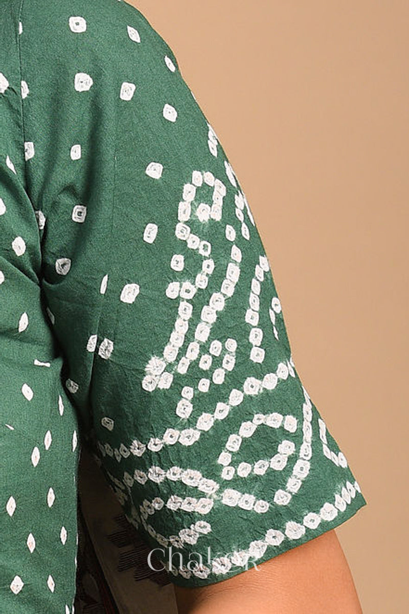 Woman wearing a handcrafted moss green bandhani cotton blouse with intricate parrot motifs and boria buttons on front.