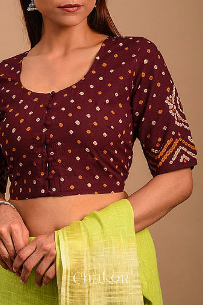 A woman wearing a traditional Maroon Bandhani Cotton Blouse with intricate mirror embroidered Keri - Paisley motifs and boria fabric buttons.