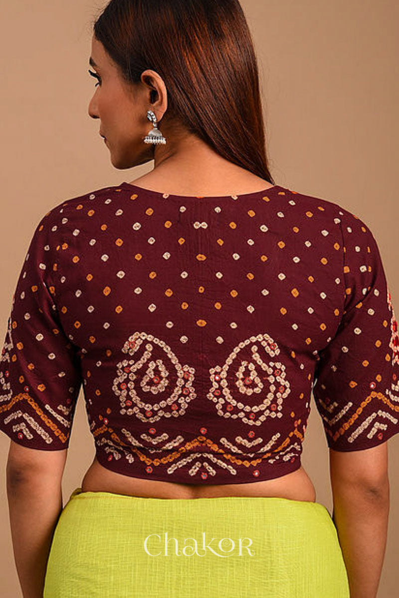 A woman wearing a traditional Maroon Bandhani Cotton Blouse with intricate mirror embroidered Keri - Paisley motifs and boria fabric buttons.
