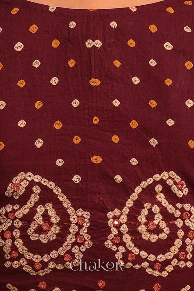 A woman wearing a traditional Maroon Bandhani Cotton Blouse with intricate mirror embroidered Keri - Paisley motifs and boria fabric buttons.