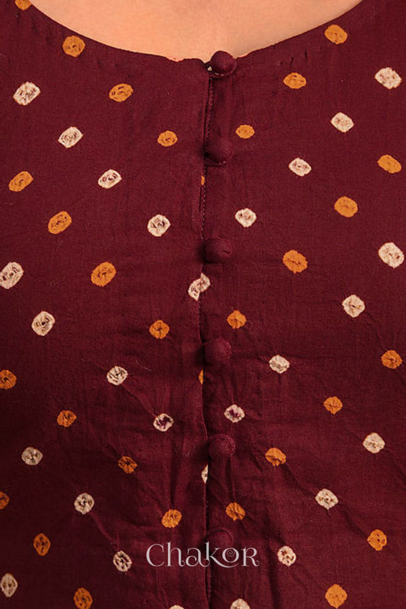 A woman wearing a traditional Maroon Bandhani Cotton Blouse with intricate mirror embroidered Keri - Paisley motifs and boria fabric buttons.