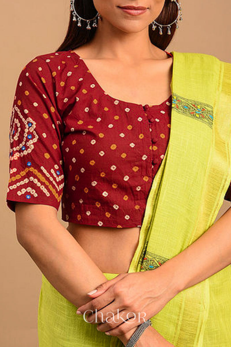 A woman wearing a traditional Red Bandhani Cotton Blouse with intricate mirror embroidered Keri - Paisley motifs and boria fabric buttons.