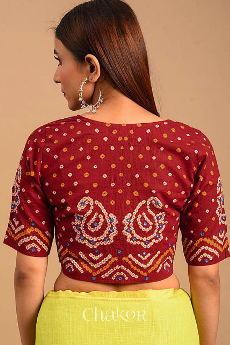 A woman wearing a traditional Red Bandhani Cotton Blouse with intricate mirror embroidered Keri - Paisley motifs and boria fabric buttons.