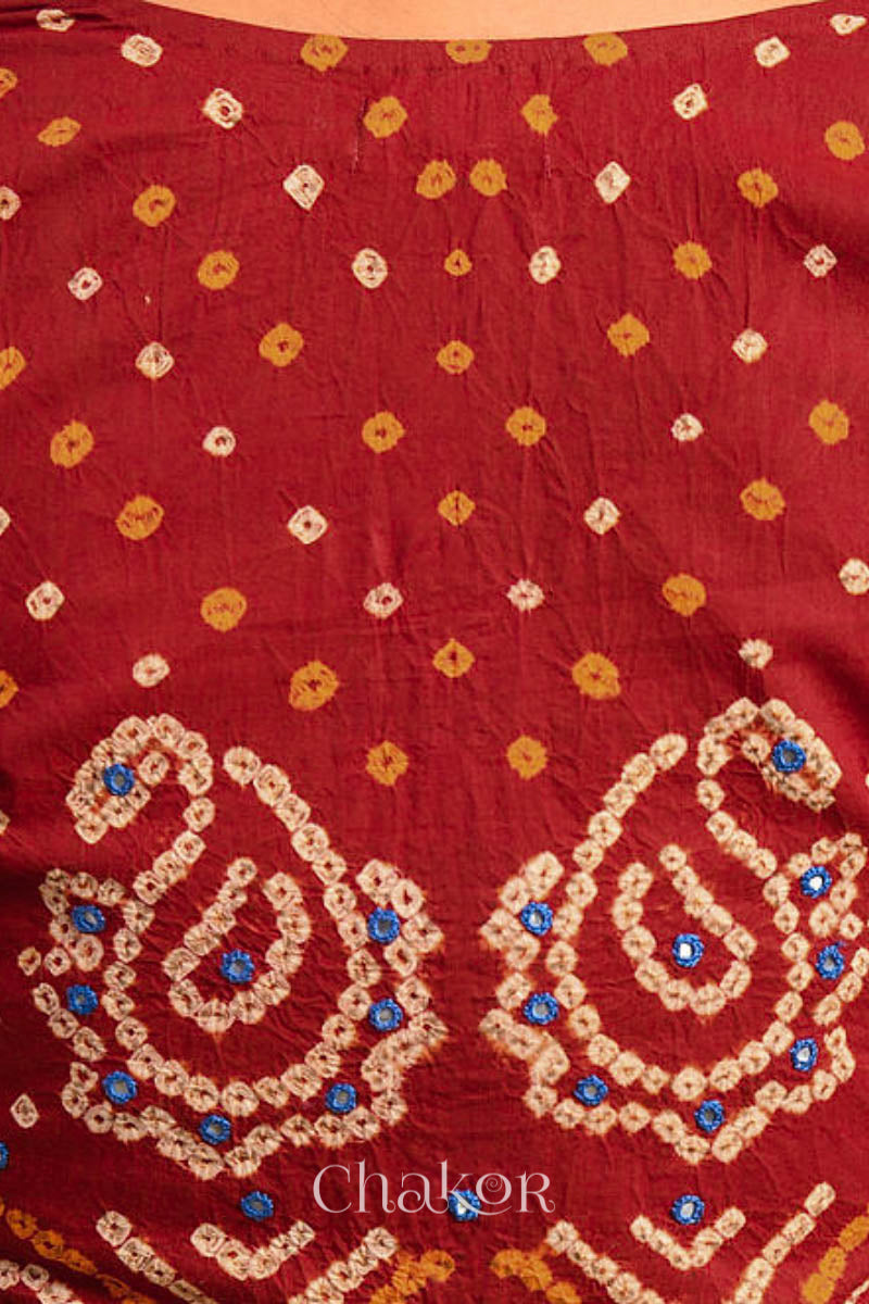 A woman wearing a traditional Red Bandhani Cotton Blouse with intricate mirror embroidered Keri - Paisley motifs and boria fabric buttons.