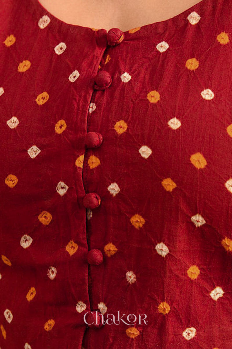 A woman wearing a traditional Red Bandhani Cotton Blouse with intricate mirror embroidered Keri - Paisley motifs and boria fabric buttons.